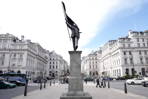 Banksy unveils faceless flag-carrying statue near Buckingham Palace
