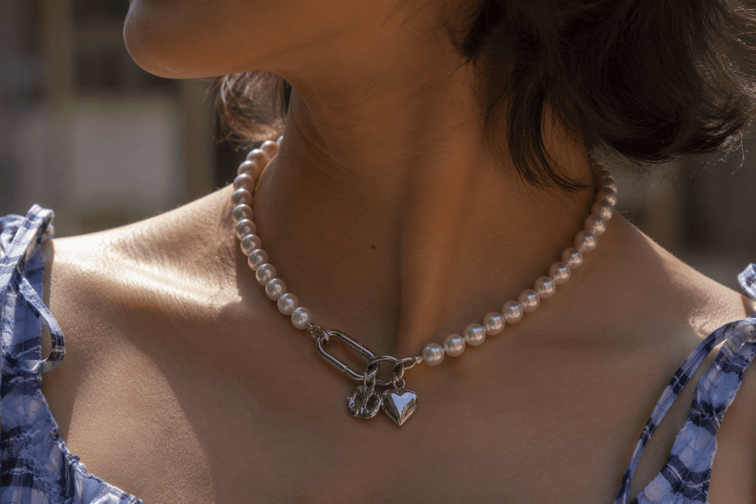 Sandy Liang’s faux pearl necklace adds silver charms and carabiner closure